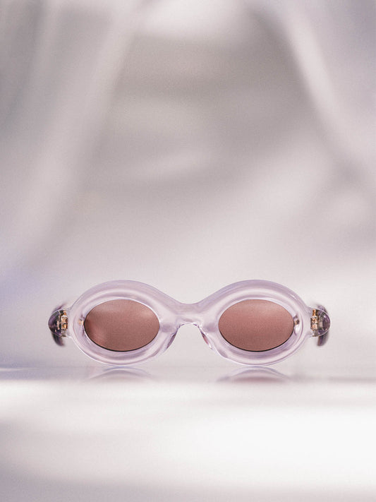 Paloceras Pebble Collection Crystal Pink RX Sunglasses, featuring round clear Pink frames with Dark Red lenses.